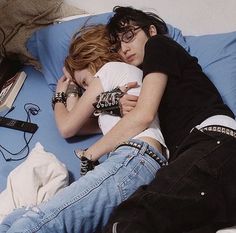 two people are laying on a bed with their arms around each other as they cuddle