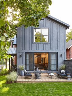 a house that is sitting on top of a wooden deck next to grass and trees