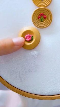 a person's finger is pressing buttons on a piece of fabric that has been stitched together