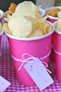 pink cups filled with chips on top of a table