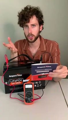 a man sitting at a table with some electronics on top of it and an electronic device in front of him