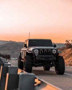 the jeep is driving down the road with its lights on