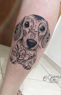 a black and white dog tattoo on the right leg, with an ornate border around it