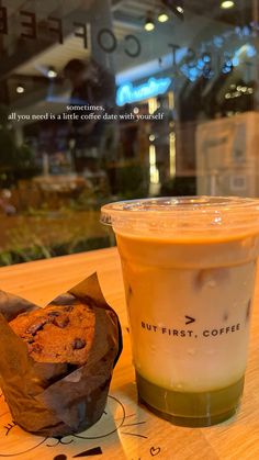 a cup of coffee next to a muffin on a table