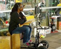 a woman sitting on top of a wooden block next to a radio microphone and laptop computer