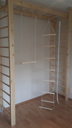 an empty room with ladders hanging from the ceiling and wood flooring on the walls