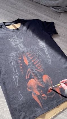 someone is painting a skeleton on a t - shirt