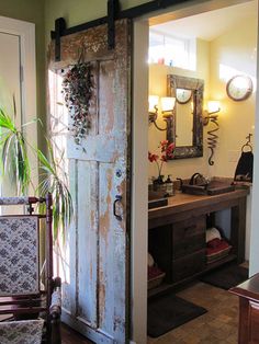 an old door is opened to reveal a bathroom with plants on the counter and mirror