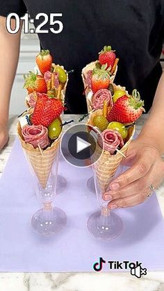 two cones filled with strawberries and green olives on top of a purple mat