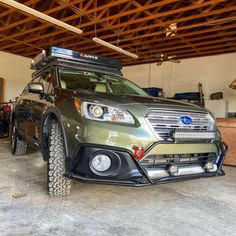 the front end of a green subarunt parked in a garage