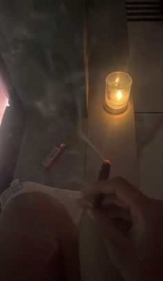 a woman laying in bed next to a lit candle