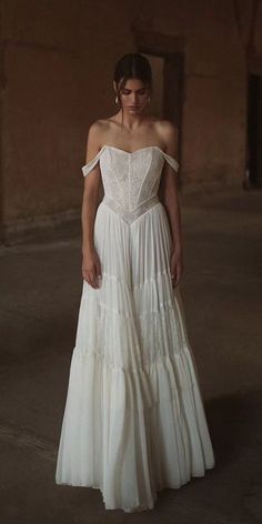 a woman wearing a white dress standing in an empty room with her hands on her hips