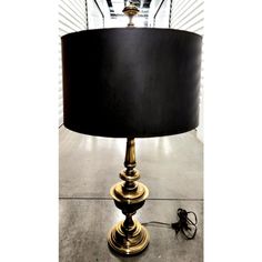 a lamp that is sitting on the floor next to a light fixture with a black shade