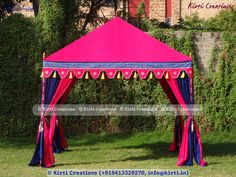 a pink and blue tent sitting on top of a lush green field