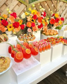 an assortment of desserts and drinks on a white table with flowers in vases