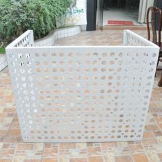 a white fence sitting on top of a brick floor next to a green planter