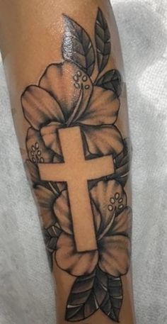 a cross and flowers tattoo on the leg