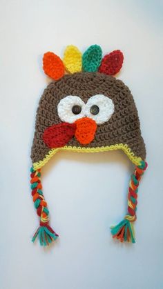 a crocheted turkey hat with multicolored pom poms on it