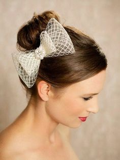 a woman wearing a white bow with a veil on her head and hair in a bun