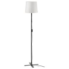 a floor lamp with a white shade on it's side and a black base