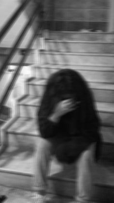 a blurry image of a woman sitting on the ground in front of some stairs