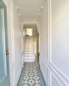 a hallway with white walls and blue flooring next to a stair case in an apartment