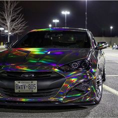 a car with holographic paint on it parked in a parking lot at night