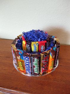 a cup filled with lots of candy sitting on top of a wooden table next to a wall