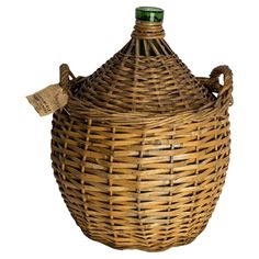 an empty wicker bottle with a tag on the lid and handle is sitting in front of a white background