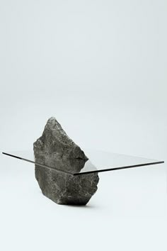 a glass table topped with a rock and a black object on top of the table