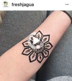 a woman's arm with a black and white tattoo design on the left forearm