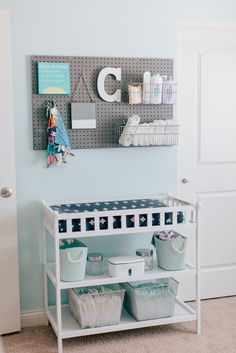 a baby's nursery room with blue walls and white shelving unit filled with items