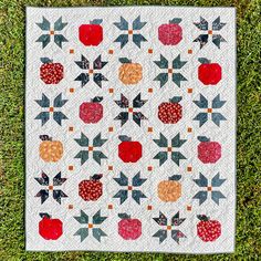 a quilted wall hanging on the grass with an apple and star design in it