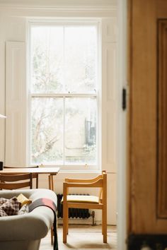 a living room filled with furniture next to a large window covered in sunlight coming through