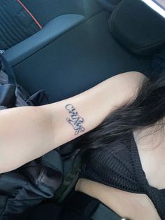 a woman with a tattoo on her arm in the back seat of a car