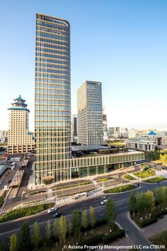 an aerial view of some very tall buildings in the city with cars driving by them