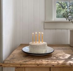 a white cake with five candles sitting on top of a wooden table