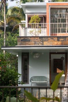 a small house with a balcony and balconies on the second floor, surrounded by greenery