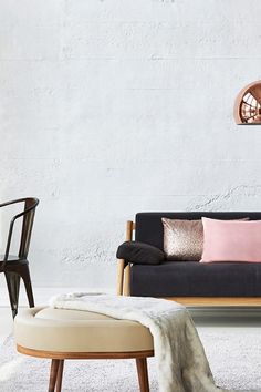 a living room with a couch, chair and ottoman next to a white brick wall