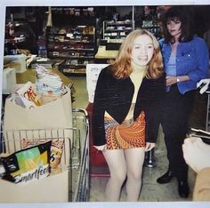 a woman standing next to a shopping cart in a store