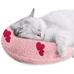 a gray and white cat sleeping on top of a pink kitty bed with red hearts