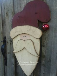 a wooden santa clause with a red hat on it's head is hanging from the side of a fence