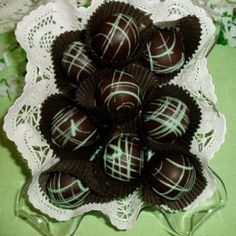 there are chocolates in the glass bowl on the lace doily with green and white designs