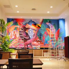 a large mural in the middle of a restaurant with ladders on it's sides