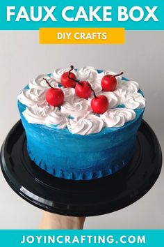 a blue cake with white frosting and cherries on top that says faux cake box diy crafts