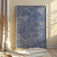 a blue and white painting sitting on top of a wooden floor next to a vase