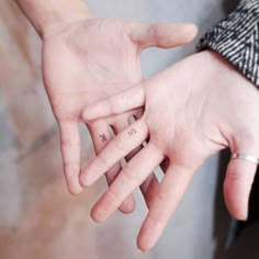 two people holding hands with initials on their fingers