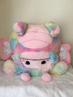 a pink stuffed animal sitting on top of a bed next to a white pillow and wall