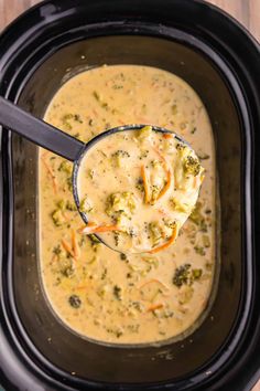 a spoon full of broccoli cheese soup in a slow cooker