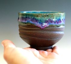 a hand holding a brown and blue cup